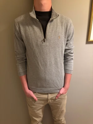 Grå half zip tröja från Polo Ralph Lauren - Snygg grå långärmad tröja från Polo Ralph Lauren med half zip och liten broderad logga på bröstet. Tröjan har en klassisk krage och är gjord i mjuk bomull, perfekt för chill dagar. Passformen är normal och materialet känns riktigt skönt mot huden. Kan inte garantera att den är äkta eftersom den är från en kompis men däremot skulle jag tro det. Storlek S. Sitter rätt så slim och är ganska gammal men inga skador alls säljer för 300 kr pris kan diskuterar