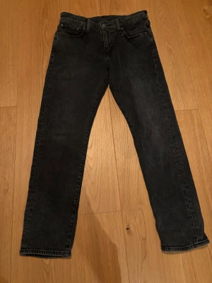 Levi's 502 svarta jeans - Svarta Levi's 511 jeans med klassisk femficksdesign och dragkedja. Jeansen har en taperd passform och raka ben, tillverkade i slitstarkt denim. Perfekt för dig som gillar en clean och tidlös look. Passar dig som vill ha jeans med lite smalare siluett.