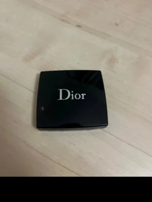 Dior guldskimrande ögonskugga - Lyxig ögonskugga från Dior i en elegant svart dosa med spegel. Färgen är en skimrande guldnyans som ger en glittrig effekt på ögonlocken. Kommer i en kompakt förpackning med applikator, perfekt att ha med i väskan.