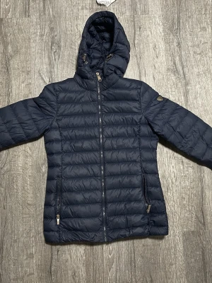 En blå dun/vind jävla från luhta  - Detta är en medel varm jacka då den kan passa i snö väder när de inte är flera minus. Fungerar prima att ha på hösten. Den är marin blå