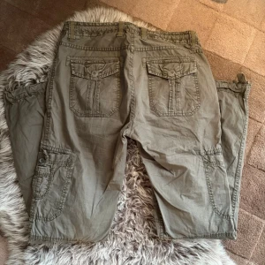 Olivgröna cargopants  - Säljer ett par olivgröna cargopants med flera stora fickor på sidorna och bak. Byxorna har dragsko i midjan och detaljerade sömmar. 