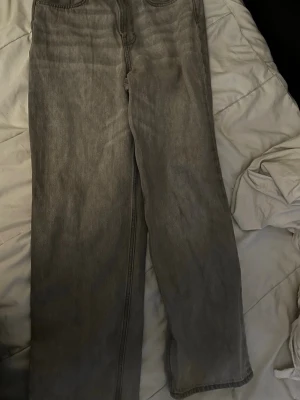 Gråa raka jeans i loose fit - Säljer ett par gråa jeans med rak passform och loose fit. Jeansen har klassisk femficksdesign och är tillverkade i ett mjukt jeanstyg. Perfekta för dig som gillar en avslappnad och trendig stil.