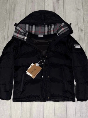 Burbery vinter jackaXväst - Snygg svart Burberry vinterjacka i storlek M, passar även S. Använd endast ett fåtal gånger och i mycket fint skick. Klassisk design med exklusiva detaljer och hög komfort – perfekt för både vardag och stad. Nypris betydligt högre.  Säljes nu för 2 499 kr.  💬 Pris kan diskuteras vid snabb affär. ⏳ Först till kvarn. ❓ Har du frågor är det bara att höra av dig! 📏 Storlek M (passar även S).