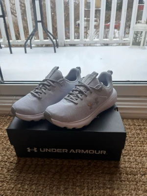 Under Armour Löparskor - Grå - Under Armour charged löparskor, gråa. Aldrig använda, stått i garderob i orginal kartong fram tills nu. Storlek 39.  Nypris: 899kr Inköpta 2025