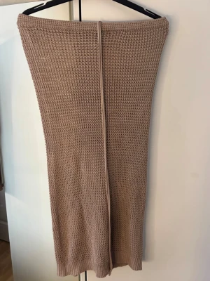 Beige stickad långkjol - Säljer en beige stickad långkjol till stranden, med rak passform och öppning därbakom. Snörre fram.