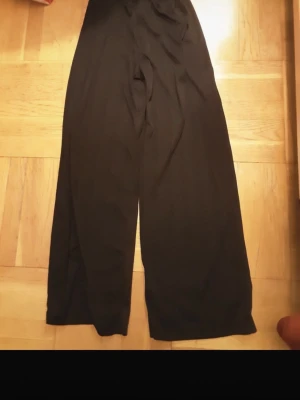 Svarta vida byxor i bomull - Säljer ett par svarta, vida byxor med hög midja. Byxorna har en avslappnad passform och är tillverkade i mjukt bomullstyg. Perfekta för en chill och stilren look.