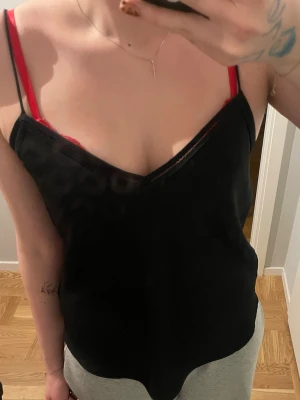 Svart linnetopp med tunna axelband - Säljer en svart linnetopp med tunna axelband och v-ringning. Toppen har en lös passform och är ärmlös, perfekt för varma dagar eller som lager på lager. Enkel och stilren design som passar till mycket. Aldrig använd