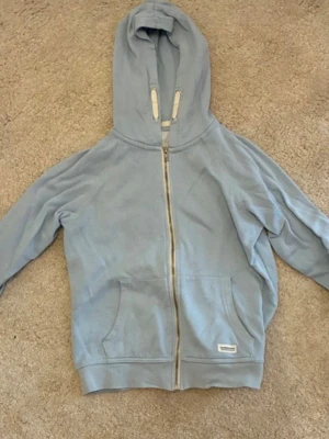 Ljusblå hoodie med dragkedja - Ljusblå hoodie från Lager 157 med dragkedja framtill och två stora fickor. Klassisk huva med snören och mjukt bomullsmaterial som känns skönt mot huden. Perfekt för en avslappnad och chill stil.