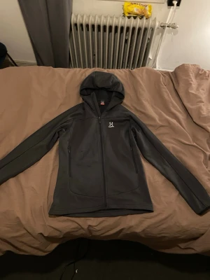 Haglöfs hoodie mörkgrå - Mörkgrå hoodie från haglöfs. Köpt för 899kr på stadium. Tvättats 3 gånger. Så knappt användts. Den har fickor med dragkedjor även 2st innerfickor!