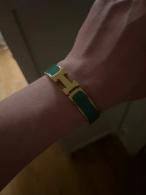 Armband Unisex  - Ett guldfärgat armband med gröna detaljer