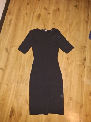 Svart ribbad midiklänning - Svart ribbad klänning med rund hals och halvlånga ärmar. Klänningen har en kroppsnära passform och är tillverkad i ett stickat material som ger en bekväm känsla. Perfekt för dig som gillar en stilren och enkel look. KLÄNNINGEN ÄR INTE SMUTSIG, DET ÄR MIN KAMERA DET ÄR FEL PÅ!🥰