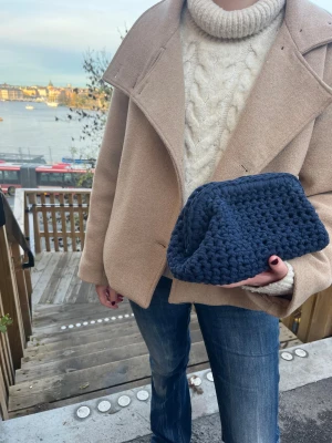 Handvirkad Clutchväska i marinblå  - Vi är ett UF-företag som säljer handvirkade Clutchväskor! 🩷 Denna väska är i färgen marinblå. Väskan har en unik form och känns både trendig och handgjord. Perfekt för dig som gillar en personlig touch på din outfit.OBS‼️ KÖPAREN STÅR FÖR FRAKTEN