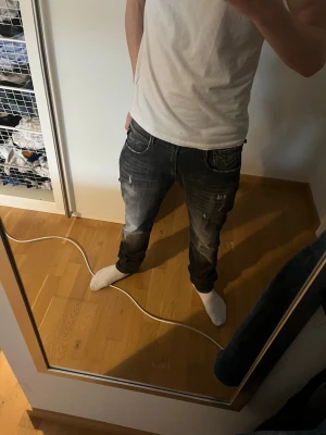 Replay Anbass mörkgrå slim jeans - Säljer ett par Replay Anbass jeans i mörkgrå tvätt med snygga slitningar och kontrastsömmar. Modellen är slim fit och har klassisk femficksdesign. Perfekta för dig som gillar en smalare passform och vill ha ett par stilrena jeans med edge.