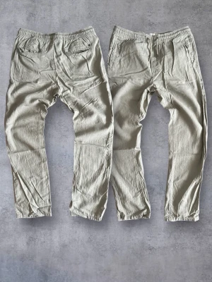 Solid Linen Pants Loose/Relaxed Fit Washed Vetiver - Jättesnygga linnebyxor från Solid med loose/relaxed passform i storlek L men passar även M. Tillverkade i ett svalt och skönt material som håller dig bekväm hela dagen. Stretchig midja med resårband och dragsko, i en stilfull design. Färg: Vetiver. Alla mått finns på bild