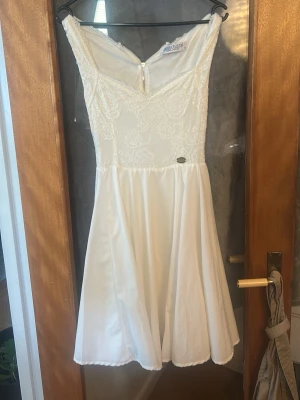 Vit spetsklänning med v-ringning - Säljer en vit kortklänning från Boohoo med v-ringning och spetsdetaljer upptill. Klänningen har en figurnära överdel, dragkedja i ryggen och en lätt utställd kjol. Perfekt för sommarens alla tillfällen!