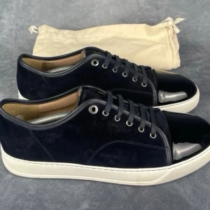 Svarta Lanvins sneakers med lackad tå - Stilrena Lanvins svarta sneakers med snörning och vit sula. Ovandelen är i mocka och tån är i blankt lackmaterial som ger en snygg kontrast. Perfekta för dig som gillar en modern och clean look.