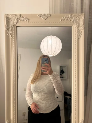 Vit långärmad topp med öppen rygg - Säljer en vit långärmad topp med unik struktur i tyget och öppen rygg. Toppen har ett diskret geometriskt mönster och är tillverkad i ett tunt, lätt material som ger en snygg och modern look. Perfekt för dig som vill sticka ut med detaljer!