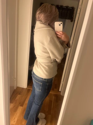 Beige omlott kappa från Vero Moda - Snygg beige kappa från Vero Moda med bred krage. Jackan har ett bälte i midjan som knyts och två fickor framtill som inte ens har blivit öppnade då de är styng som man måste sprätta upp. Har aldrig använt den då jag tyckte den inte passar mig.