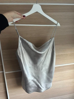 Silvrig festtopp! - Lyxig draperad silvertopp som faller som vatten på huden! Fint skick! Står stl 34 i men stämmer mer överens med stl  36. 