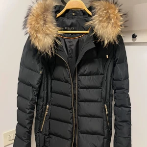 Jacka från Hollies - Jackan är i väldigt bra skick! Innehåller 80% dun & 20% fjäder. Jackan är egentligen storlek 42 men då Hollies jackor är väldigt små i storleken motsvarar den storlek 38 enligt mig. Kan funka för 40 med om man gillar att ha jackan tight. Nypris 5199kr. 