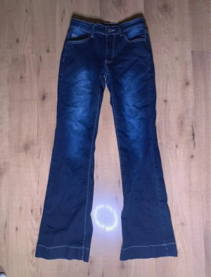 Blå bootcut jeans med kontrastsömmar - Snygga blå jeans med bootcut passform och markerade kontrastsömmar. Klassisk femficksmodell med hög midja och raka ben som blir vidare nedtill. Jeansen har en cool tvätt med ljusare partier framtill och är tillverkade i jeansmaterial.