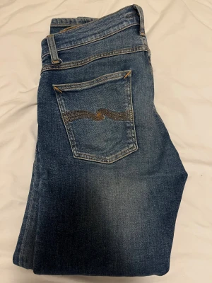 Blå jeans från  Nudie Jeans - Snygga blåa nudie jeans med fem fickor, inga defekter. Jeansen är true to size och inga problem med dem.