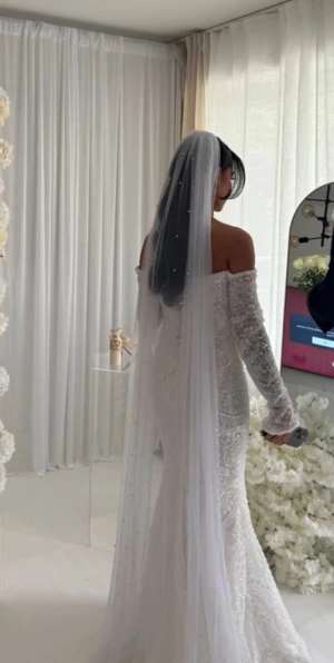 Vit pärlbroderad lång bröllopsklänning - Magisk vit bröllopsklänning med offshoulder och långa ärmar, täckt av pärlbroderier och glittrande detaljer. Figurnära passform som framhäver siluetten och lång släp. Perfekt för dig som vill ha en riktigt lyxig och unik look på din stora dag. Använd i 2 timmar innan jag bytte om till en annan klänning.  Skräddarsydd. 34/36 styrs av korsett .  Priset kan diskuteras Nypris 47900