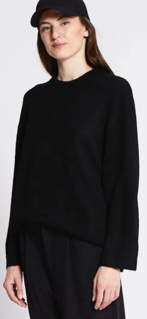 Svart stickad tröja med rund hals - En svart stickad tröja med rund hals och lång ärm. Tröjan har en loose passform och är enkel i designen, perfekt för lager-på-lager och chill stil. Passar dig som gillar minimalistiskt och tidlöst.