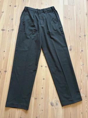 Grå kostymbyxor från Only & Sons - Snygga grå kostymbyxor från Only & Sons med loose fit. Byxorna har pressveck, hällor för bälte och en klassisk rak siluett. Perfekta för dig som gillar en avslappnad men ändå stilren look.