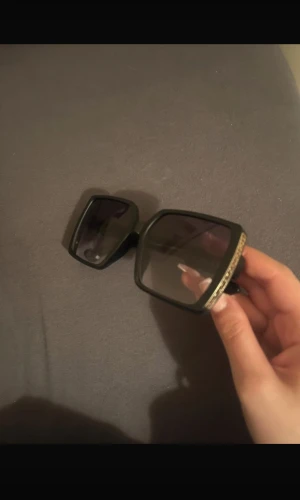 Svarta fyrkantiga solglasögon med gulddetalj - Stora, fyrkantiga solglasögon i svart med markerad ram och cool guldfärgad detalj upptill på bågen. Glasen är mörka och ger en riktigt trendig vibe. Perfekta för dig som vill sticka ut och addera lite edge till din stil.