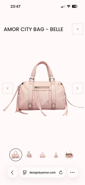 Ljusrosa handväska från Amor - Snygg ljusrosa handväska från Amor med flätade handtag, silverfärgade detaljer och dragkedja upptill. Väskan har flera fack inuti och dekorativa remmar med spännen på framsidan. Perfekt storlek för att få plats med allt du behöver. Perfekt skick inte använt. För bilder eller frågor hör av dig!