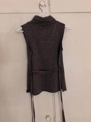 Brun stickad väst från ZARA - Brun topp från Zara med polokrage och knytband i midjan. Använd en gång,i jätte bra skick!