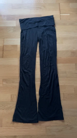 Svarta yogapants byxor från Gina Tricot - Svarta bootcut byxor från Gina Tricot i mjukt bomullsmaterial. De är midwaist med bred linning och långa, utsvängda ben. Perfekta för dig som gillar en avslappnad och trendig look.