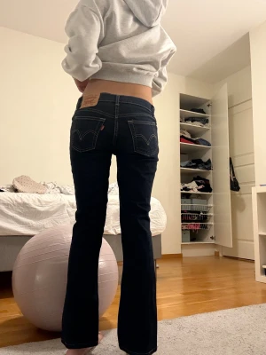 Levis mörkblå bootcut jeans - Säljer ett par Levis jeans i mörkblå tvätt med klassiska kontrastsömmar och bootcut-ben. Lågmidjade med fem fickor och Levis patch bak. Snygg passform som sitter tajt upptill och släpper vid vaden. Perfekt för dig som gillar retrovibe och stilrena jeans.