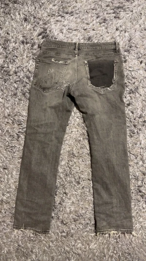 Grå slitna jeans från H& Essentials - Grå jeans med regular fit, modell N°2. Byxorna har slitna detaljer, lagade hål och patchar.