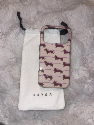 Burga iPhone 17 Pro Skal - Snyggt och tåligt skal från Burga till iPhone 17 Pro med sött tax-mönster. Skalet är i nyskick utan synligt slitage och levereras med originalpåse. Ger bra skydd och har exakta utskärningar för knappar och kamera.