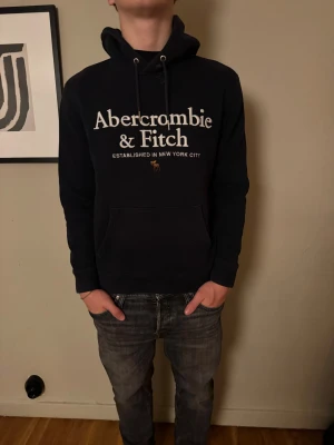 Svart hoodie Abercrombie & Fitch S - Tja! Nu säljer jag denna jätte snygga hoodien från Abercrombie & Fitch. Perfekt för chill dagar och enkel att matcha med jeans. Har en liten defekt vid snören så som ni kan se på bilderna