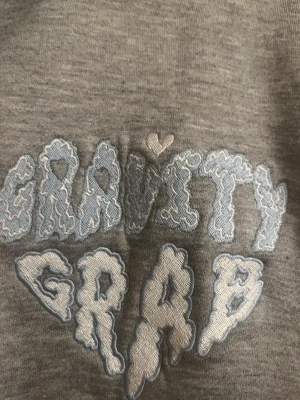 Gravity grab kofta - En perfekt kofta för alla årstider. Koftan är varm och skön med rep på varje sida. Den har vit färg som design. Den har lite svarta fläckar some smutsiga.