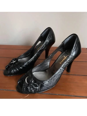 Svarta klackskor  - Säljer ett par svarta klackskor från Stefano med öppen tå och snygg detalj framtill. De har några defekter därav priset. Storlek 38