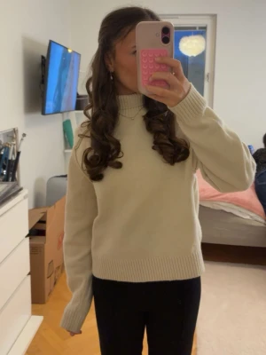 vit  stickad polotröja - Säljer en vit  stickad polotröja med lång ärm och ribbade muddar. Tröjan har en hög krage och är perfekt för kyliga dagar. Enkel och stilren design som är lätt att matcha med olika outfits.