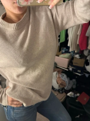 Beige stickad tröja med rund hals - Mysig beige stickad tröja med rund halsringning och ribbade muddar. Perfekt för lager-på-lager och passar till jeans eller kjol. Enkel och stilren design som funkar till många outfits.