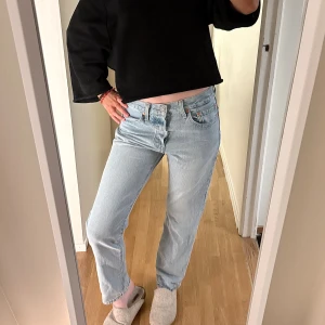 Levi's 501 ljusblå jeans W26 L28 - Ljusblå Levi's 501 jeans med klassisk knappgylf och raka ben. Modellen har hög midja och är tillverkad i slitstark bomull. Perfekt passform och tidlös look, med snygga detaljer som synliga sömmar och metallknappar. Ett måste för jeansälskaren!