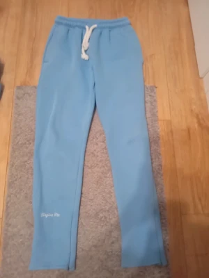 Blå mjukisbyxor Forgive Me - Snygga ljusblå mjukisbyxor från Forgive Me med vit snörning i midjan och elastisk resår. Byxorna har tryckt logga på benet och ett stort grafiskt tryck på baksidan. Mjukt material som är perfekt för chill och häng.