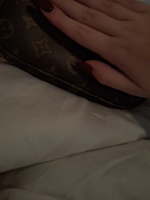  brun axelväska med kedja - Säljer en snygg brun axelväska klassiskt guldfärgad kedja. Väskan är liten och smidig, perfekt för att bära det viktigaste. Materialet är skinn och detaljerna är i guldmetall. Ikonisk design som alltid är trendig.