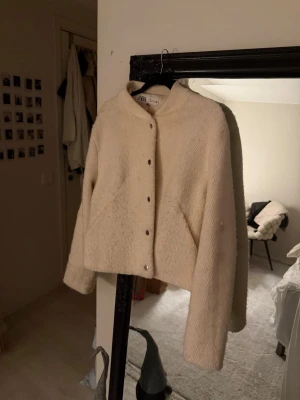 Beige teddyjacka från Zara, storlek L - Säljer en beige teddyjacka från Zara i storlek L. Jackan har en croppad passform, ribbad krage och knappar framtill. Jackan har en fläck. Den går bort, bara inte orkat försöka. Jackan är inte välanvänd