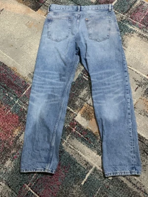 Blå relaxed jeans från H&M 32/32 - Säljer ett par ljusblå relaxed fit jeans från H&M i storlek 32/32. Klassisk femficksmodell med raka ben och normal midja. Jeansen har en avslappnad passform och är tillverkade i bomull med snygg tvättad look.