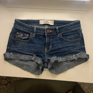 Lågmidjade jeansshorts från Hollister - Säljer ett par klassiska blå jeansshorts från Hollister med upprullade och fransiga benslut. Shortsen är korta, lågmidjade och har fem fickor. Säljer då dem är för små för mig💗💗(använda endast fåtals gånger)
