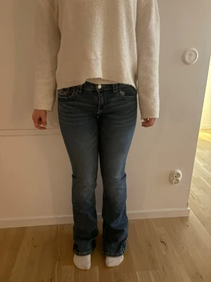 Blå bootcut jeans med kontrastsömmar - Säljer ett par blå jeans medsnygga kontrastsömmar. Jeansen har låg midja och är boot cut. Storlek 164 på barn avdelningen 