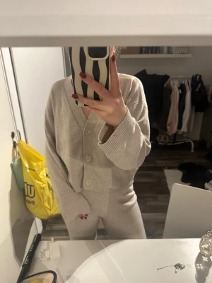 Beige mjukisbyxor med loose fit och stickat topp till - Säljer ett par beige mjukisbyxor med loose fit och rak passform. Byxorna är tillverkade i mjukt bomullsmaterial och har en enkel, stilren look utan synliga detaljer. Perfekta för chill dagar hemma eller när du vill vara extra bekväm. Säljer även en matchande stickad tröja till