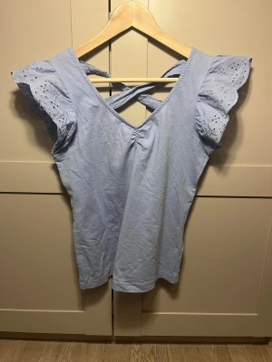 Jättefin blå volangtopp - Jättefin blå topp med ett litet resårband på bysten, mönstrade, korta volangärmar och knytning i ryggen. Blusen är i bomull och känns otroligt skön. Inga tecken på användning finns. 